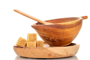 A few cubes of brown sugar with a wooden cup with a saucer and a wooden spoon, macro, isolated on a white background.