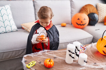 Adorable caucasian boy having halloween party holding little pumpkin at home