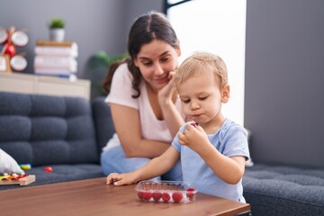 Mother and son eating raspberries sitting on sofa at home