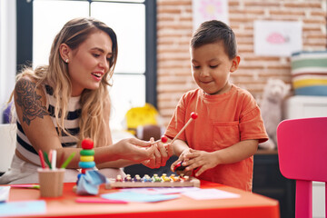 Teacher and toddler playing xylophone sitting on table at kindergarten