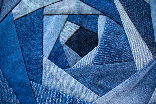 Jeans background, patchwork texture. The new life of old jeans. Recycling old clothes. Denim quilt for a pillow in the crazy-rose technique