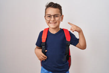 Little hispanic boy wearing glasses and student backpack smiling happy pointing with hand and finger