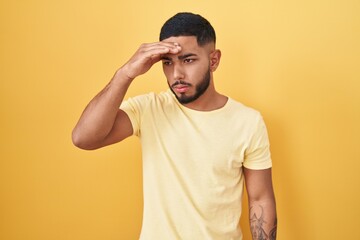 Fototapeta na wymiar Young hispanic man standing over yellow background worried and stressed about a problem with hand on forehead, nervous and anxious for crisis