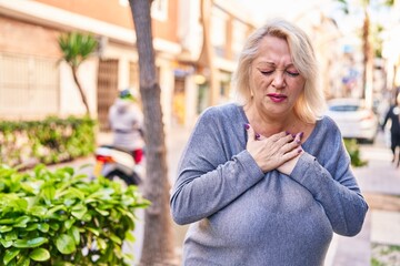 Middle age blonde woman coughing at street