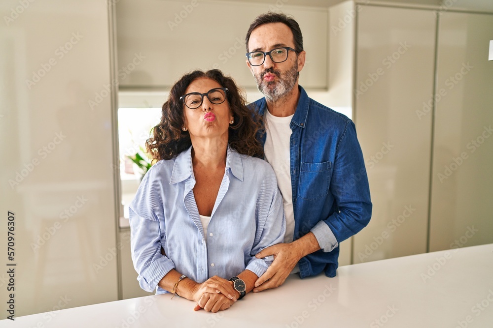 Poster Middle age couple standing together looking at the camera blowing a kiss on air being lovely and sexy. love expression.