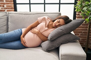 Fototapeta na wymiar Young latin woman pregnant sleeping on sofa at home