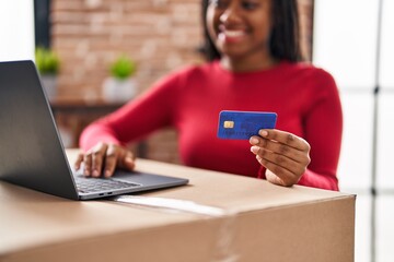 African american woman smiling confident using laptop and credit card at new home