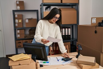 Young hispanic woman ecommerce business worker read document at office