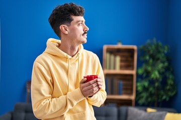 Young caucasian man holding cup of coffee with relaxed expression at home