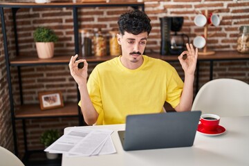 Young caucasian man doing yoga exercise sitting on table at home