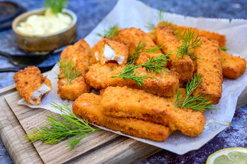 Close up of   Crispy breaded  deep fried fish fingers with breadcrumbs served  with remoulade sauce and  lemon Cod Fish Nuggets on rustic wood table background