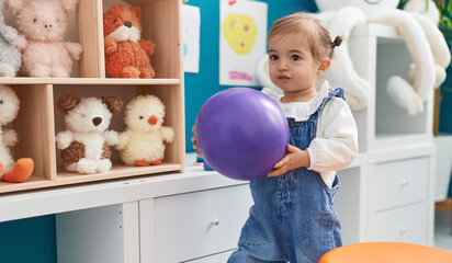 Adorable blonde toddler smiling confident holding ball at kindergarten