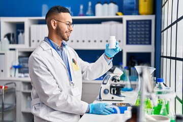 Fototapeta premium African american man scientist smiling confident weighing pills at laboratory