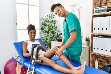 Obraz premium Man and woman wearing physiotherapist uniform having rehab session massaging leg at physiotherapy clinic