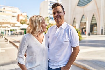 Middle age man and woman couple hugging each other standing at street