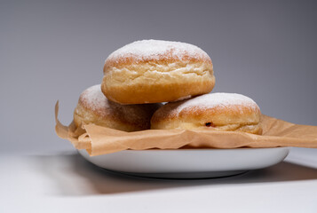 Polish pączki deep-fried doughnuts. Celebrating Fat Thursday, Tłusty czwartek feast, traditional day in Poland. Pączek food, powdered sugar topped and filled with rose hip jam.