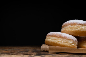 Polish pączki deep-fried doughnuts with copy space. Celebrating Fat Thursday (Tłusty czwartek) feast, traditional day in Poland. Pączek food, powdered sugar topped and filled with rose hip jam.
