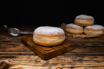 Polish pączki deep-fried doughnuts. Celebrating Fat Thursday, Tłusty czwartek feast, traditional day in Poland. Pączek food, powdered sugar topped and filled with rose hip jam.