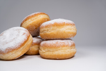 Polish pączki deep-fried doughnuts. Celebrating Fat Thursday, Tłusty czwartek feast, traditional day in Poland. Pączek food, powdered sugar topped and filled with rose hip jam.	