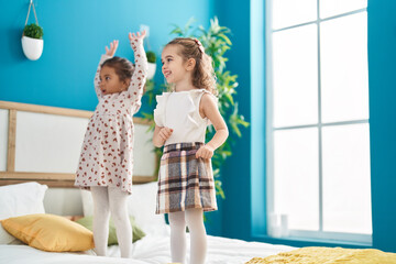 Two kids smiling confident dancing on bed at bedroom