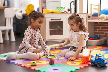 Fototapeta premium Two kids playing xylophone sitting on floor at kindergarten