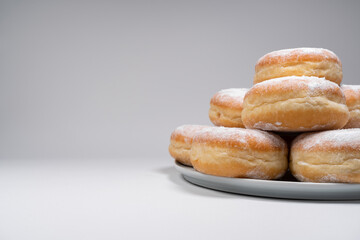Polish pączki deep-fried doughnuts with copy space. Celebrating Fat Thursday (Tłusty czwartek) feast, traditional day in Poland. Pączek food, powdered sugar topped and filled with rose hip jam.