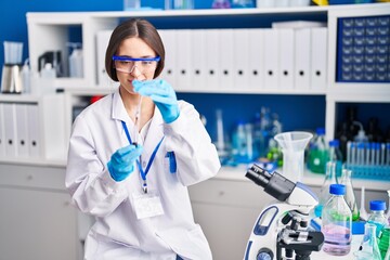 Young beautiful hispanic woman scientist pouring blood on test tube at laboratory