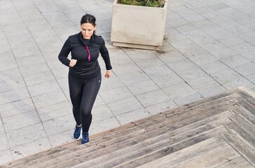 Young hispanic woman wearing sportswear running at street
