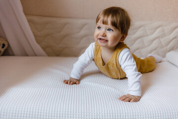 Naklejka premium Cute baby boy lying on white sheet at home, boy sitting on the bed.