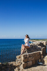 Female tourist resting on the walls of a fortress in Cyprus
