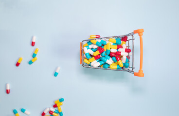 Shopping basket and pills on blue background. The concept of buying drugs online, delivery of medical devices. Copy space for text. 