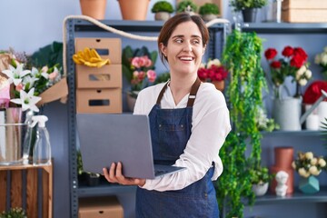 Young woman florist smiling confident using laptop at florist shop