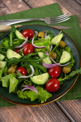 Healthy vegetable salad of fresh tomato, cucumber, onion, spinach, lettuce and sesame on plate. Diet menu. Top view.