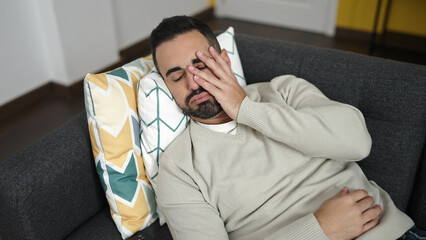 Obraz premium Young hispanic man lying on sofa with worry expression at home
