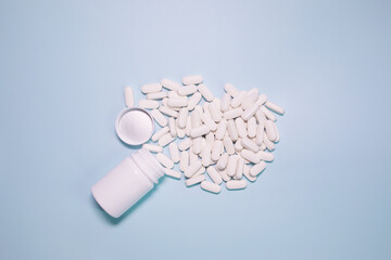 Vitamin pills flat lay on a blue background in a plastic white bottle. Vitamin medical prescription. 