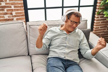 Middle age man listening to music sitting on sofa at home