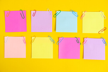 Colorful stickers for notes and paper clips yellow background.