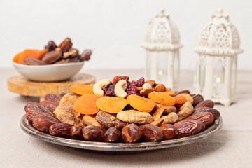 Ramadan Kareem and iftar muslim food, holiday concept. Trays with nuts and dried fruits and latterns with candles. Celebration idea