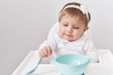 Adorable blonde baby sitting on highchair over isolated white background