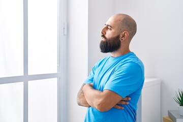 Young bald man standing with arms crossed gesture stressed at home