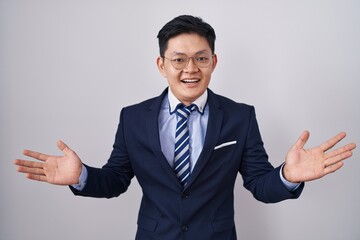 Young asian man wearing business suit and tie celebrating crazy and amazed for success with arms raised and open eyes screaming excited. winner concept