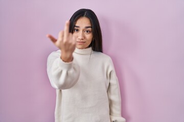 Young south asian woman standing over pink background showing middle finger, impolite and rude fuck...