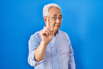 Hispanic senior man wearing glasses pointing with finger up and angry expression, showing no gesture