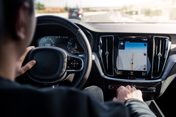 Young adult driving a new technology car with gps screen safely on the motorway. Concept of travel, transportation with car, luxury vehicle.