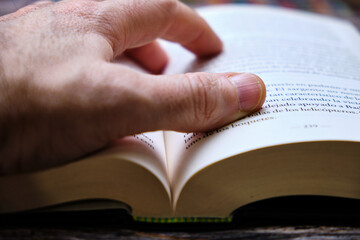 Close-up of a man's hand consulting a book.