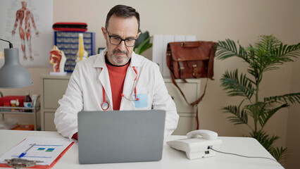 Middle age man doctor using laptop working at clinic