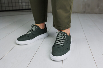 Male legs in pants and green casual sneakers. Men's fashionable shoes