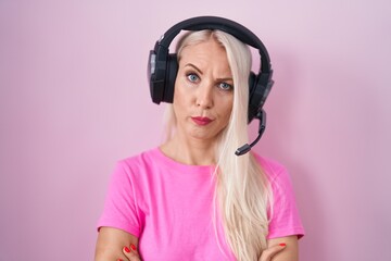 Caucasian woman listening to music using headphones skeptic and nervous, disapproving expression on face with crossed arms. negative person.