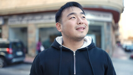 Young chinese man smiling confident looking to the side at street