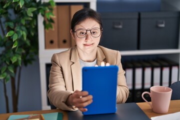 Young woman with down syndrome business worker using touchpad working at office